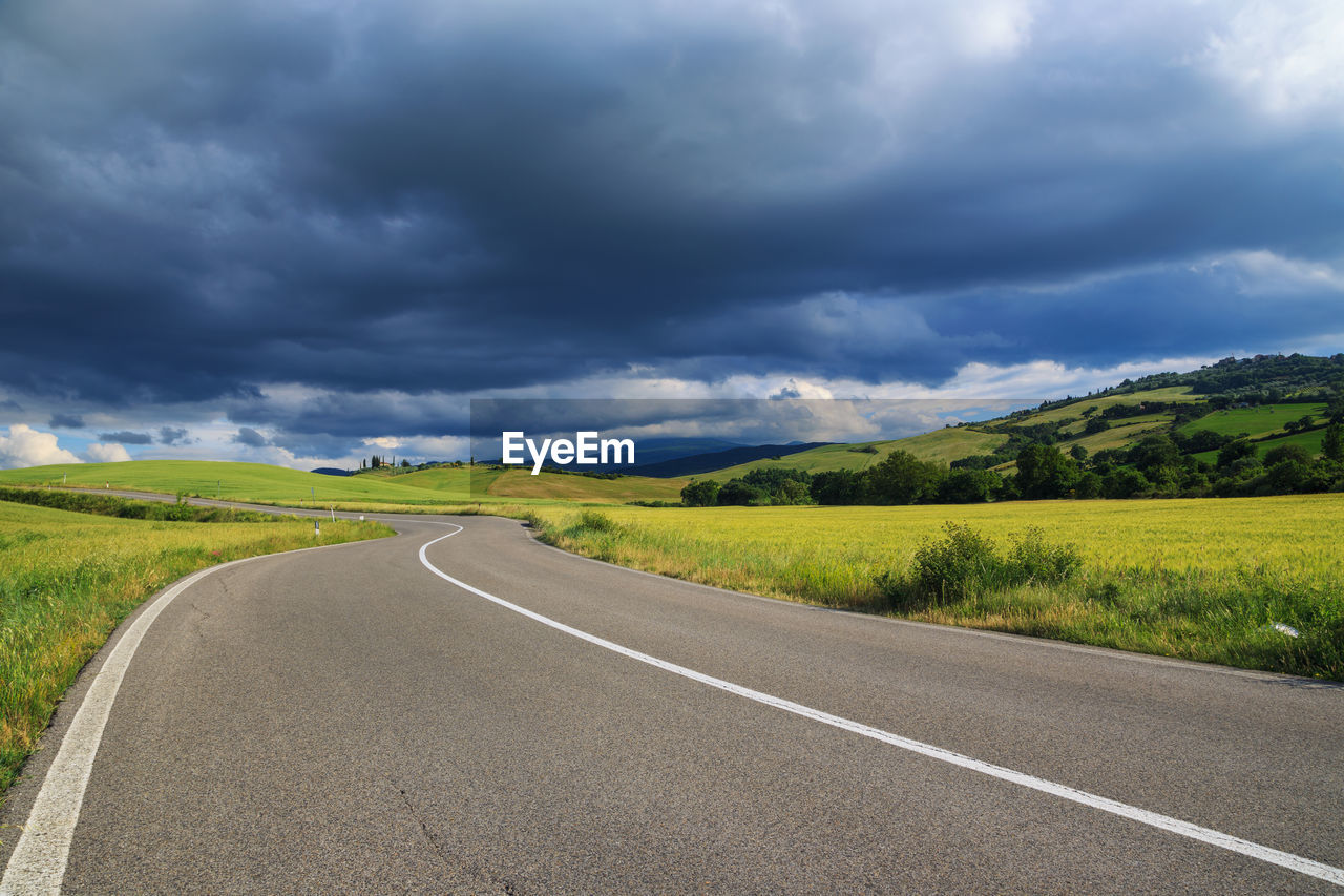 ROAD BY FIELD AGAINST SKY