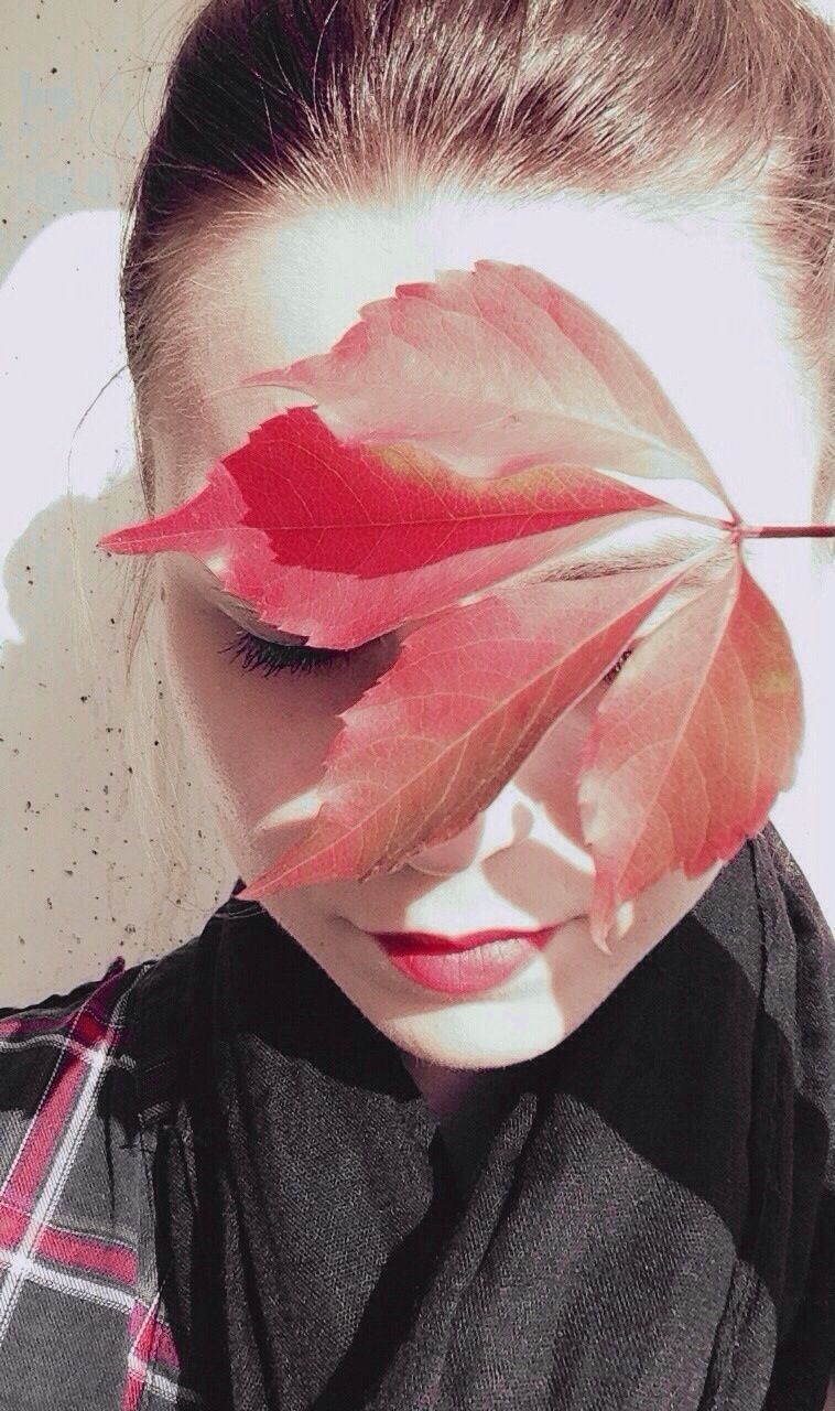 Woman with red leaf on face