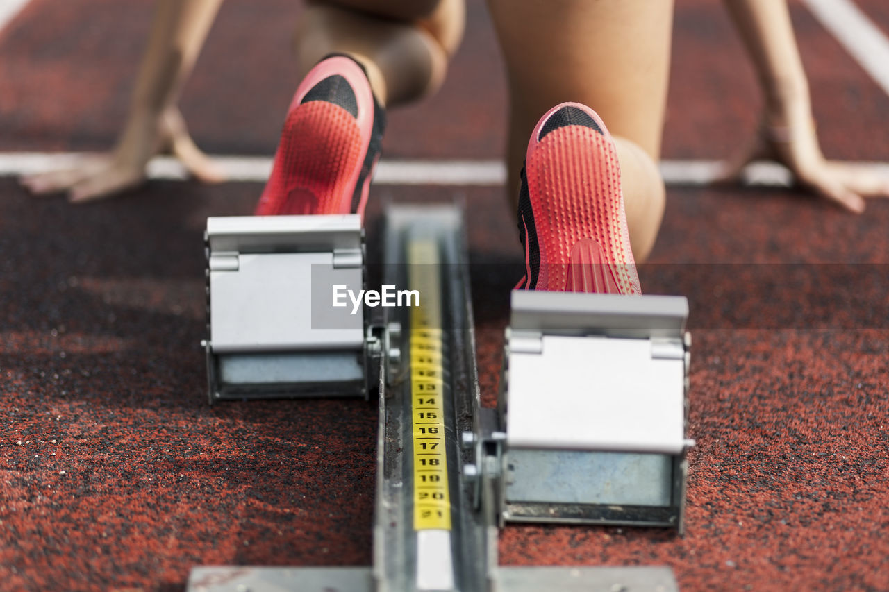 Teenage runner kneeling on starting block, close up