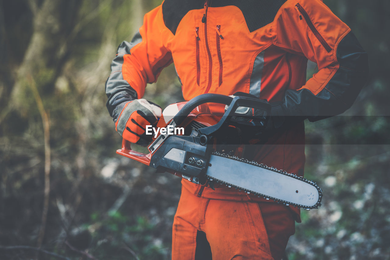 Man holding a chainsaw cut the  trees. lumberjack at work gardener working outdoors  in the forest. 