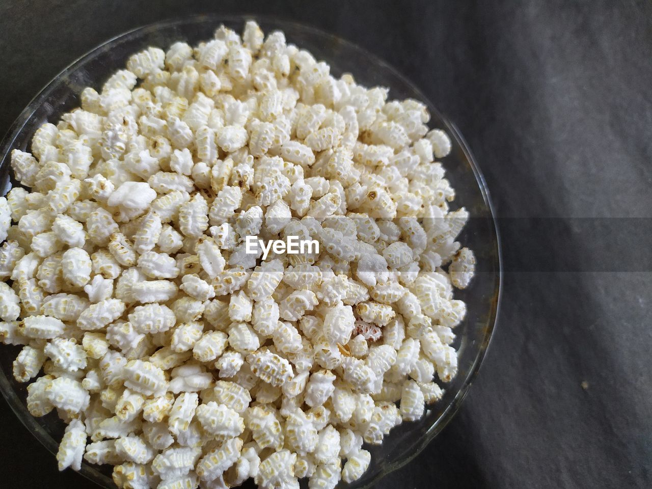 Indian parched rice in a glass bowl for light breakfast, black background.