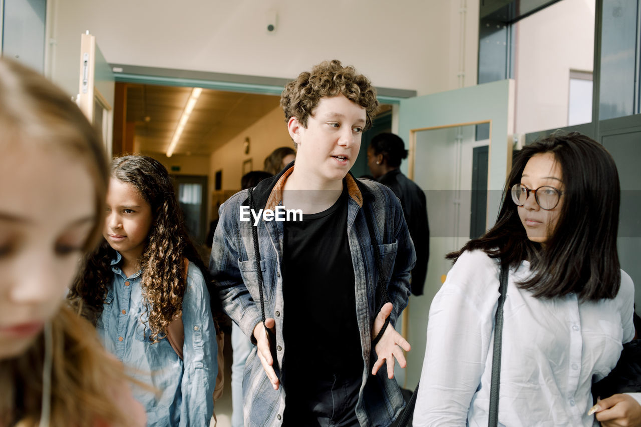 Male gesturing while talking to female friend in school corridor during lunch break