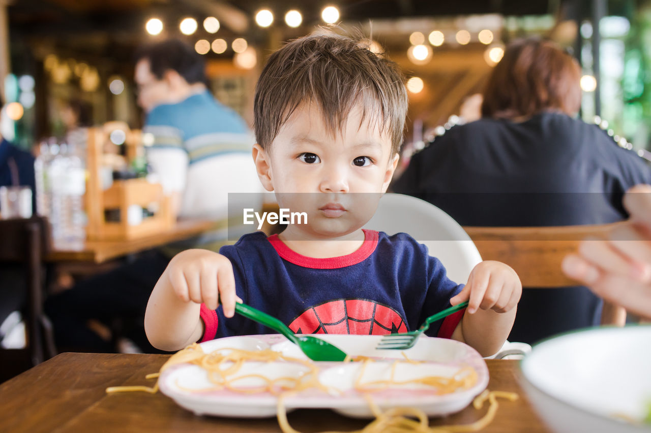 Cute baby boy having meal at restaurant