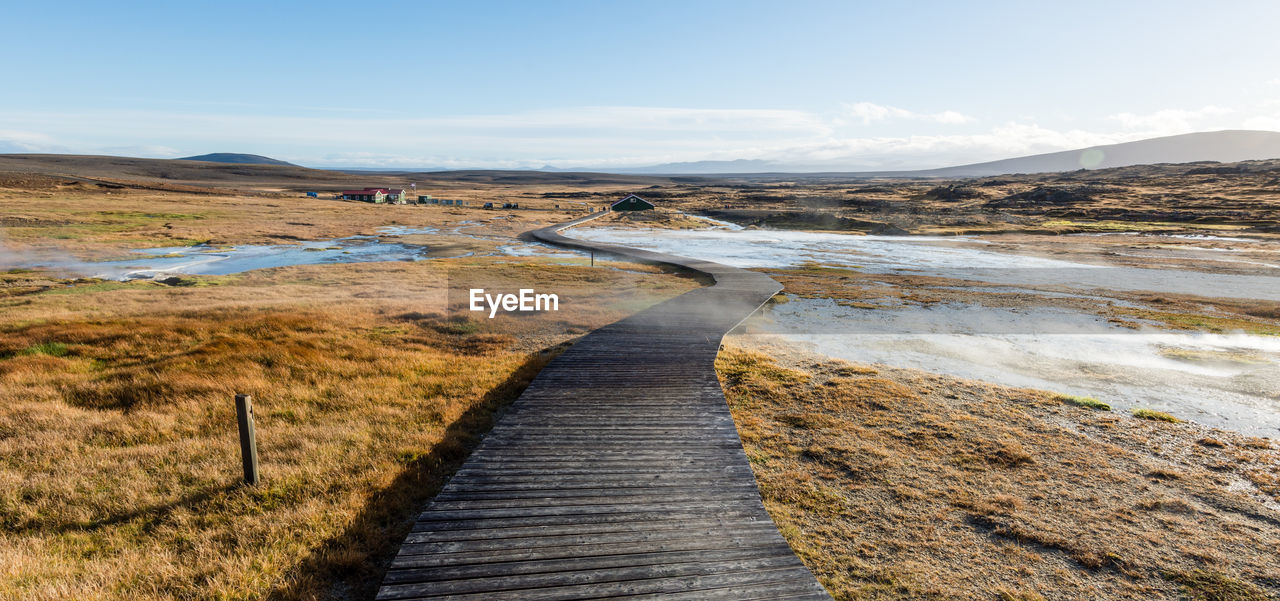 Walkway amidst landscape against sky