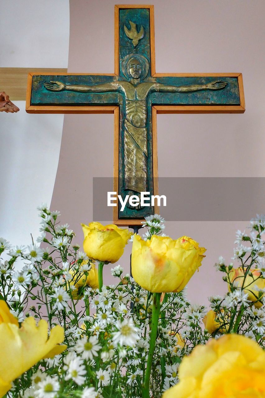 Low angle view of flowers against cross at church