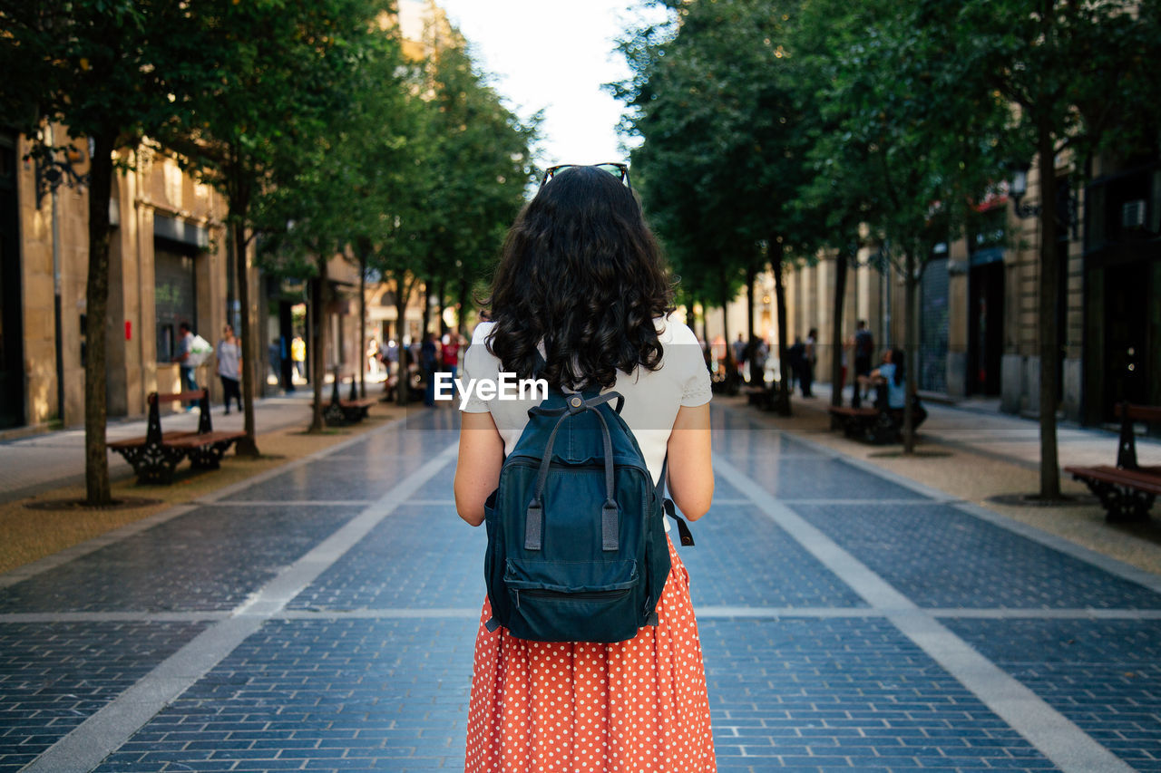 Rear view of woman standing on street in city