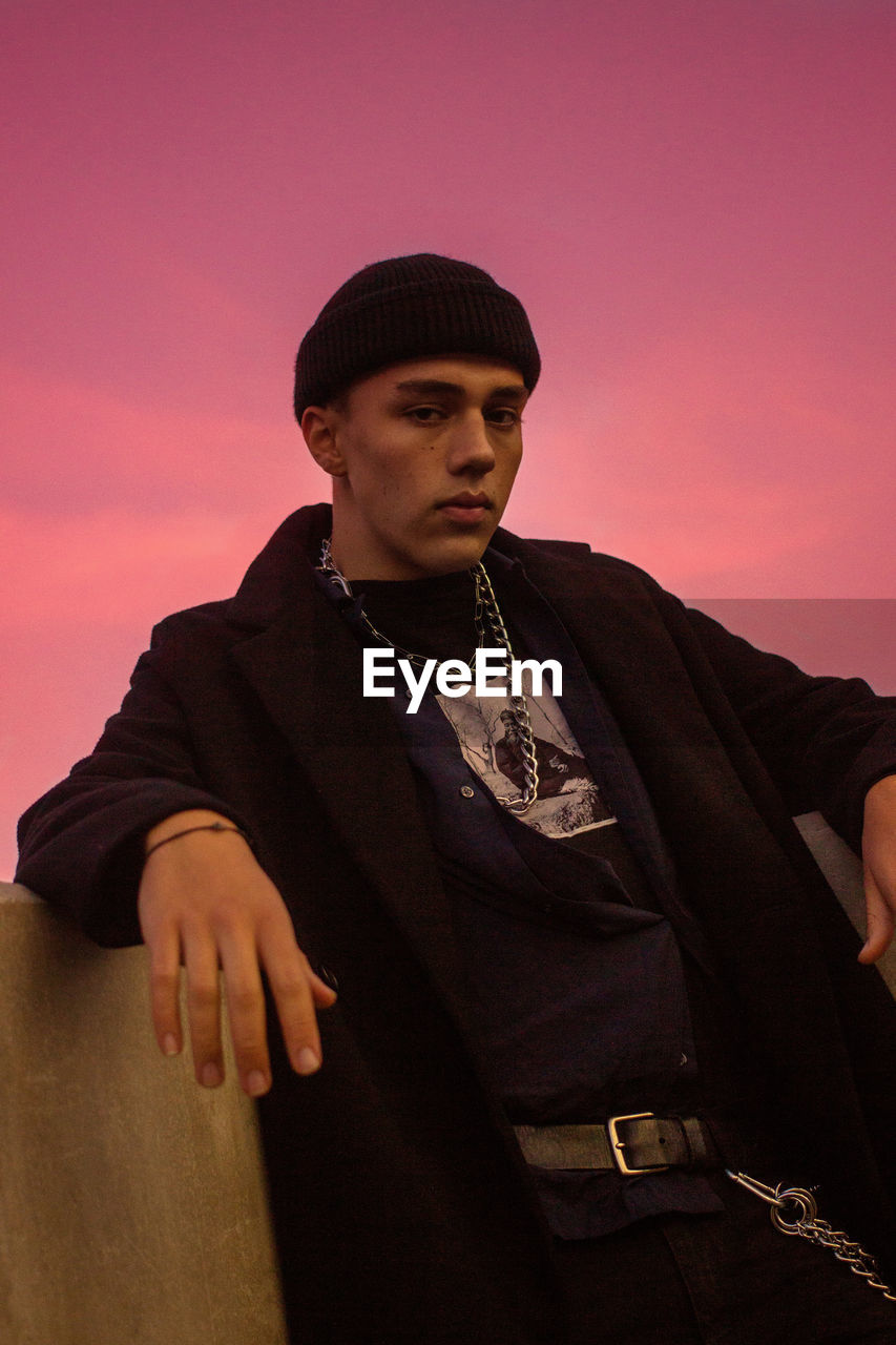 PORTRAIT OF YOUNG MAN STANDING AGAINST SKY DURING SUNSET