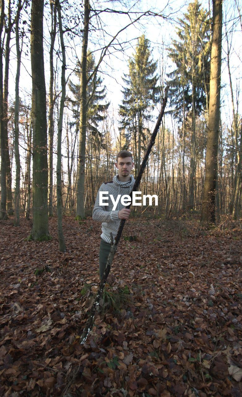 Digital composite image of man standing in forest during autumn