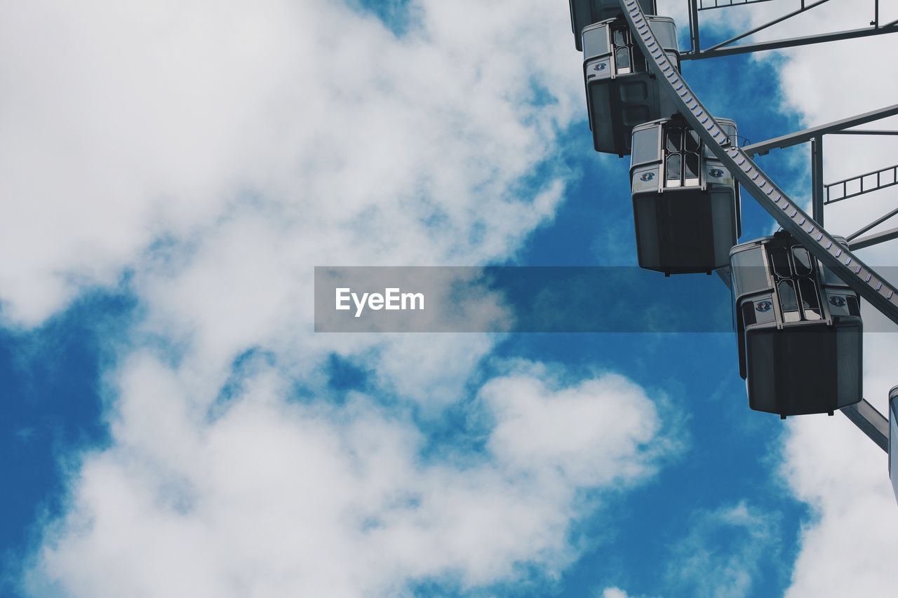 Low angle view of ferris wheel against cloudy sky