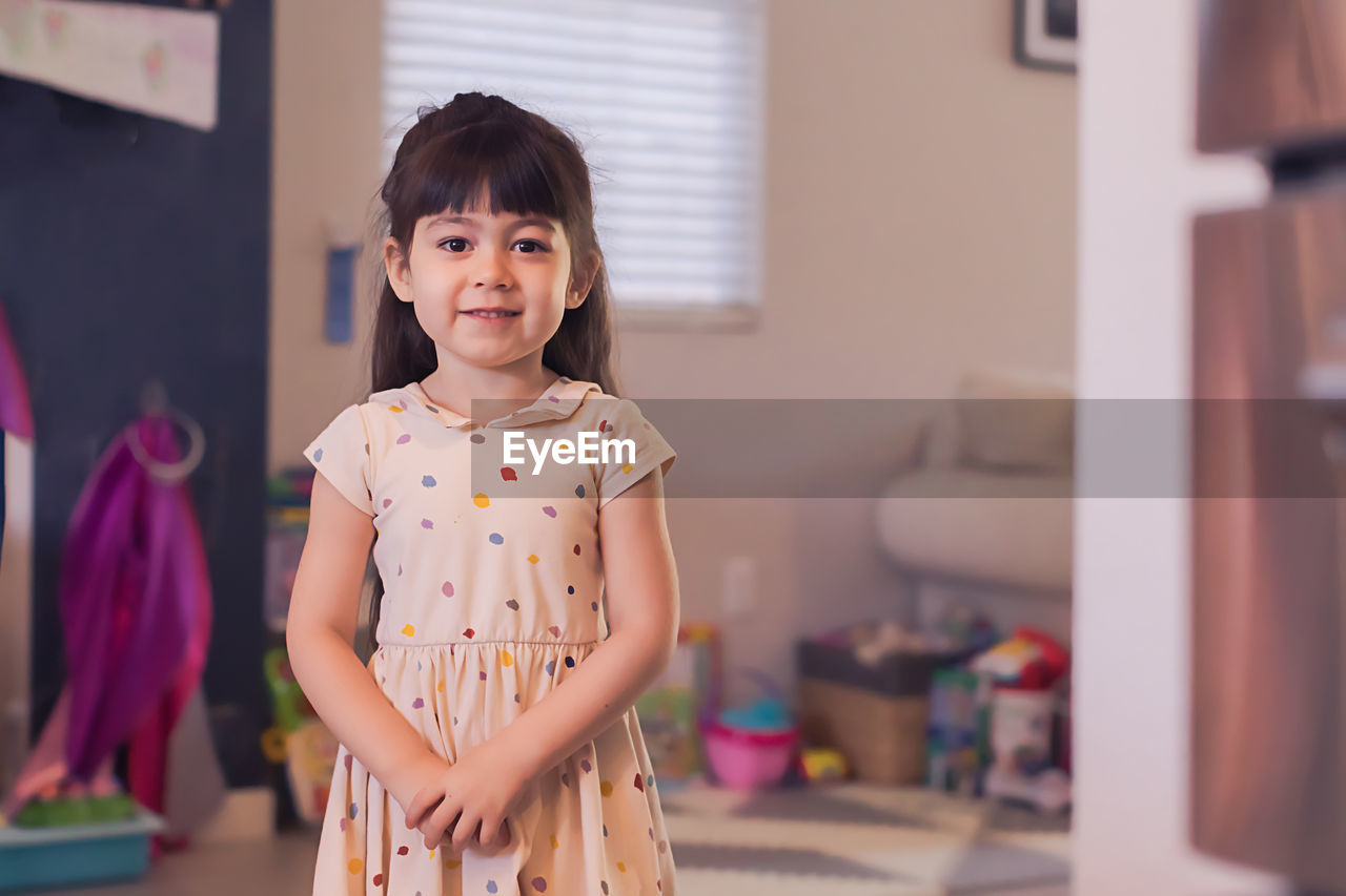 Serious four year old girl in polka dot dress looking at camera.