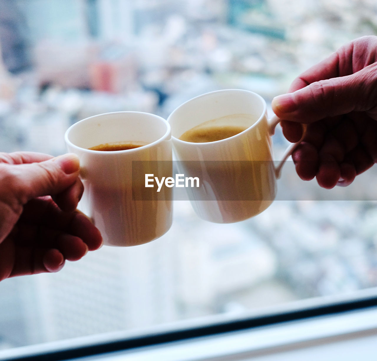 Cropped image of two persons holding coffee cup