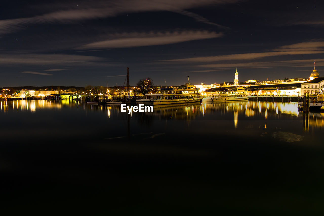 Scenic view of lake by illuminated city at night