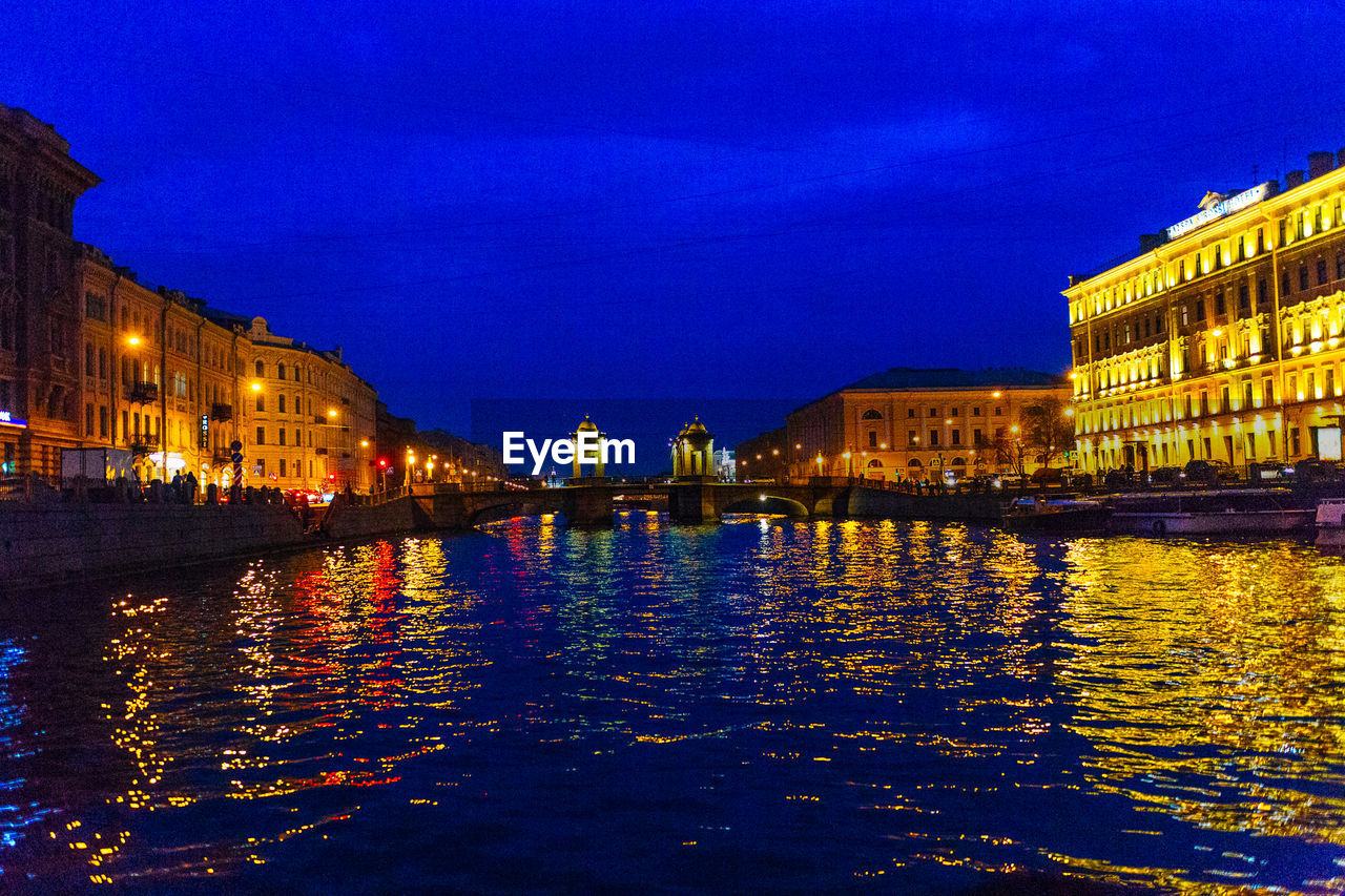 ILLUMINATED BUILDINGS WITH WATERFRONT AT NIGHT