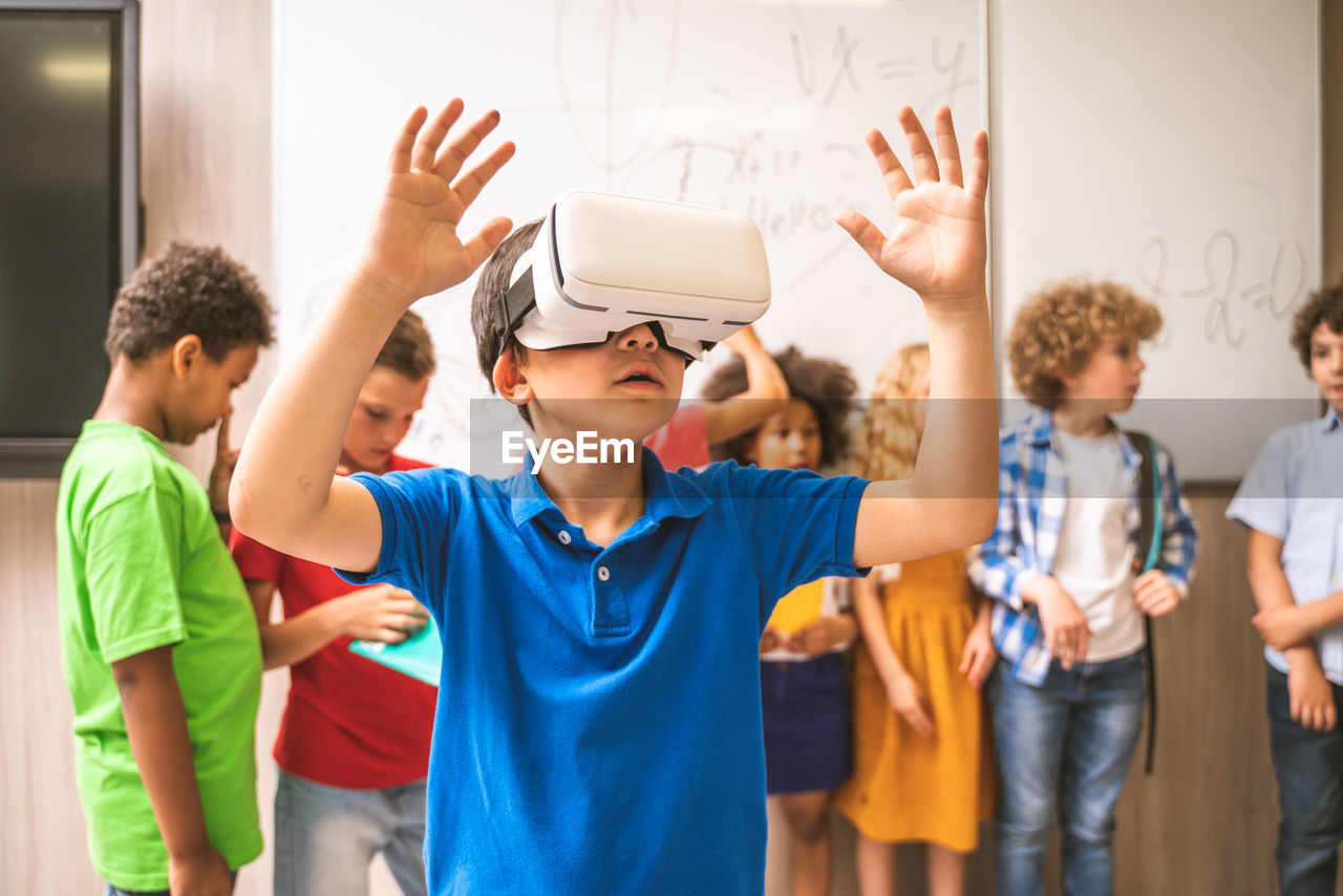 Cute boy using virtual reality simulator in classroom