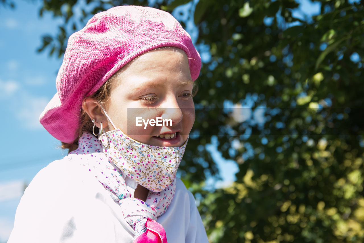 Close-up of cute smiling girl wearing mask looking down