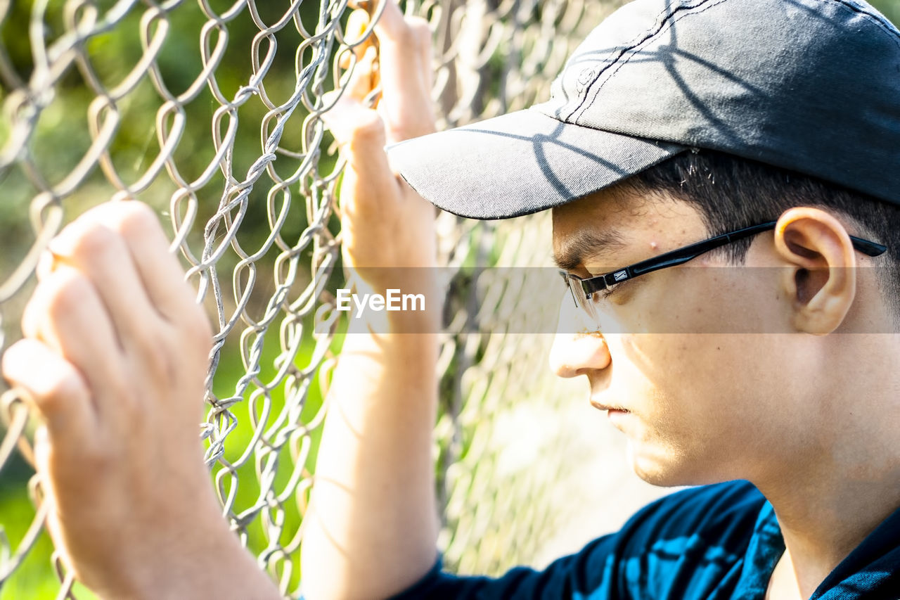 Close-up of thoughtful boy by fence