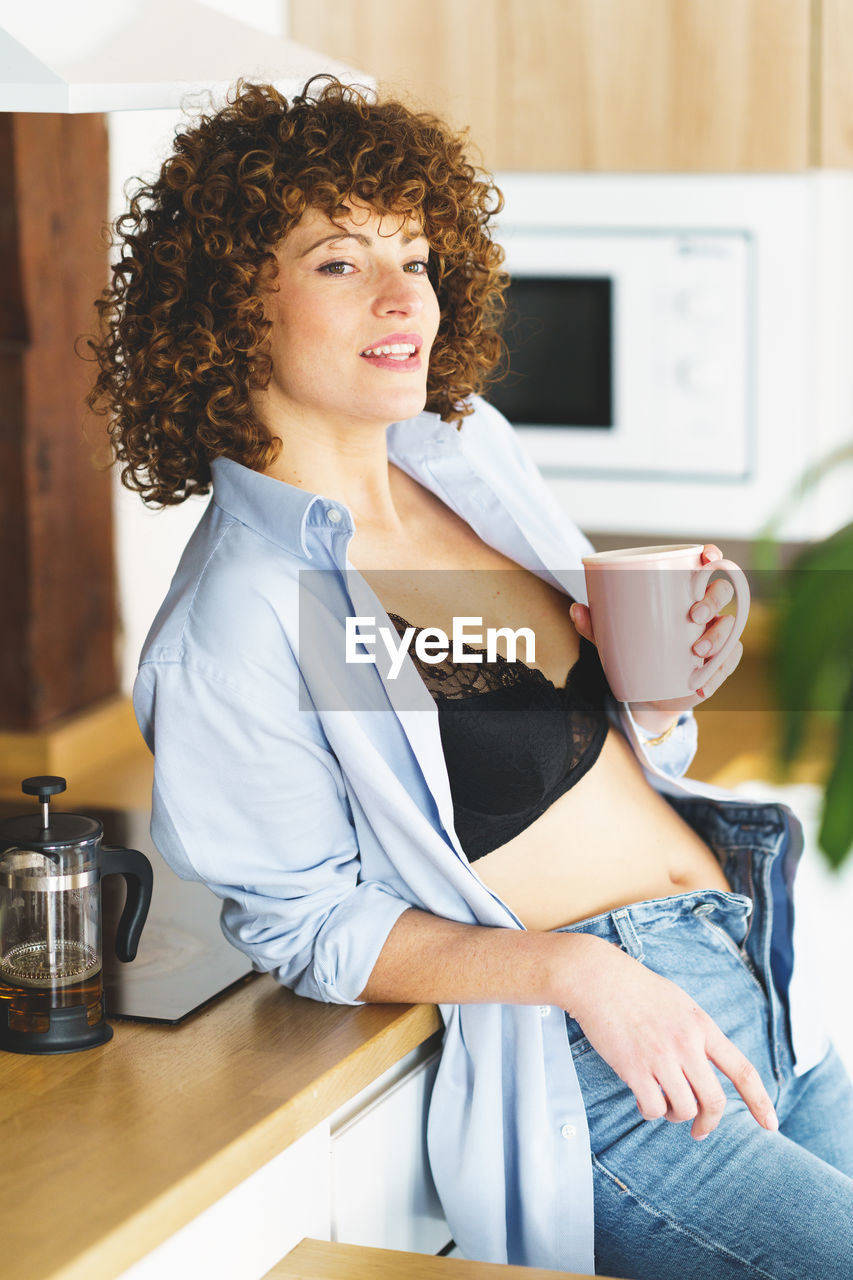 portrait of young woman using mobile phone while sitting on table at home