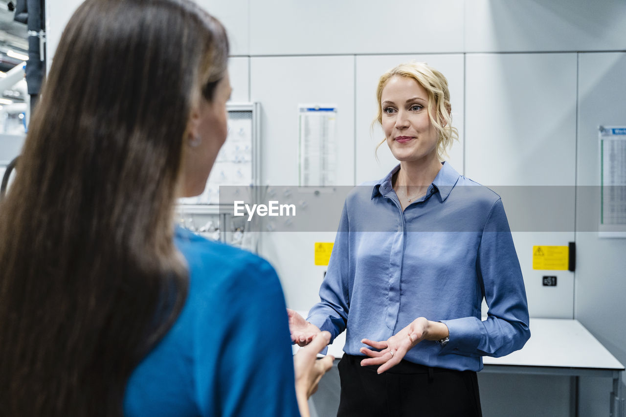 Businesswoman discussing with coworker at automated factory