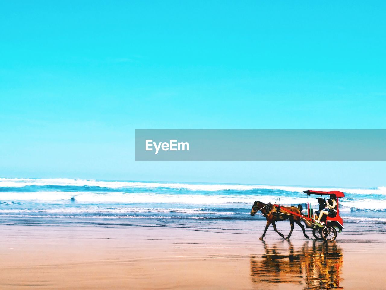 MAN RIDING HORSE ON BEACH AGAINST SEA AGAINST SKY