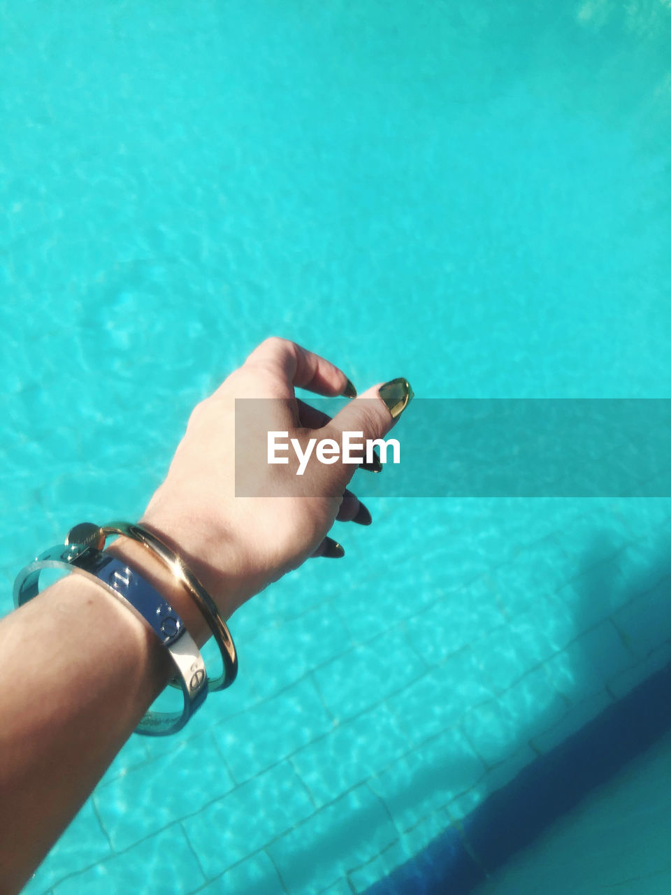 LOW SECTION OF PERSON HAND IN SWIMMING POOL