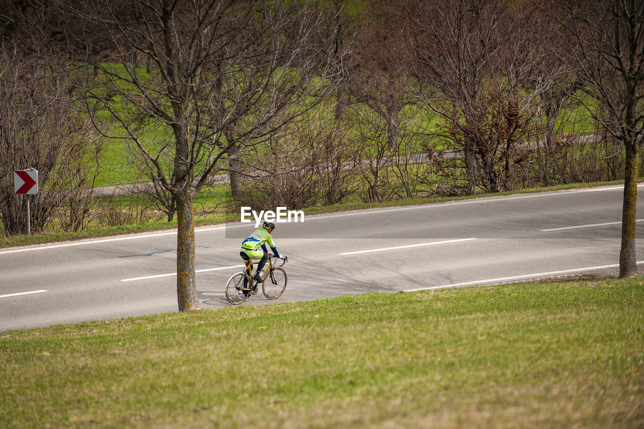 MAN RIDING BICYCLE BY ROAD