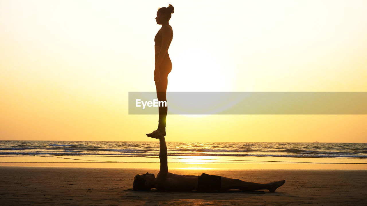 Man and woman doing yoga at beach