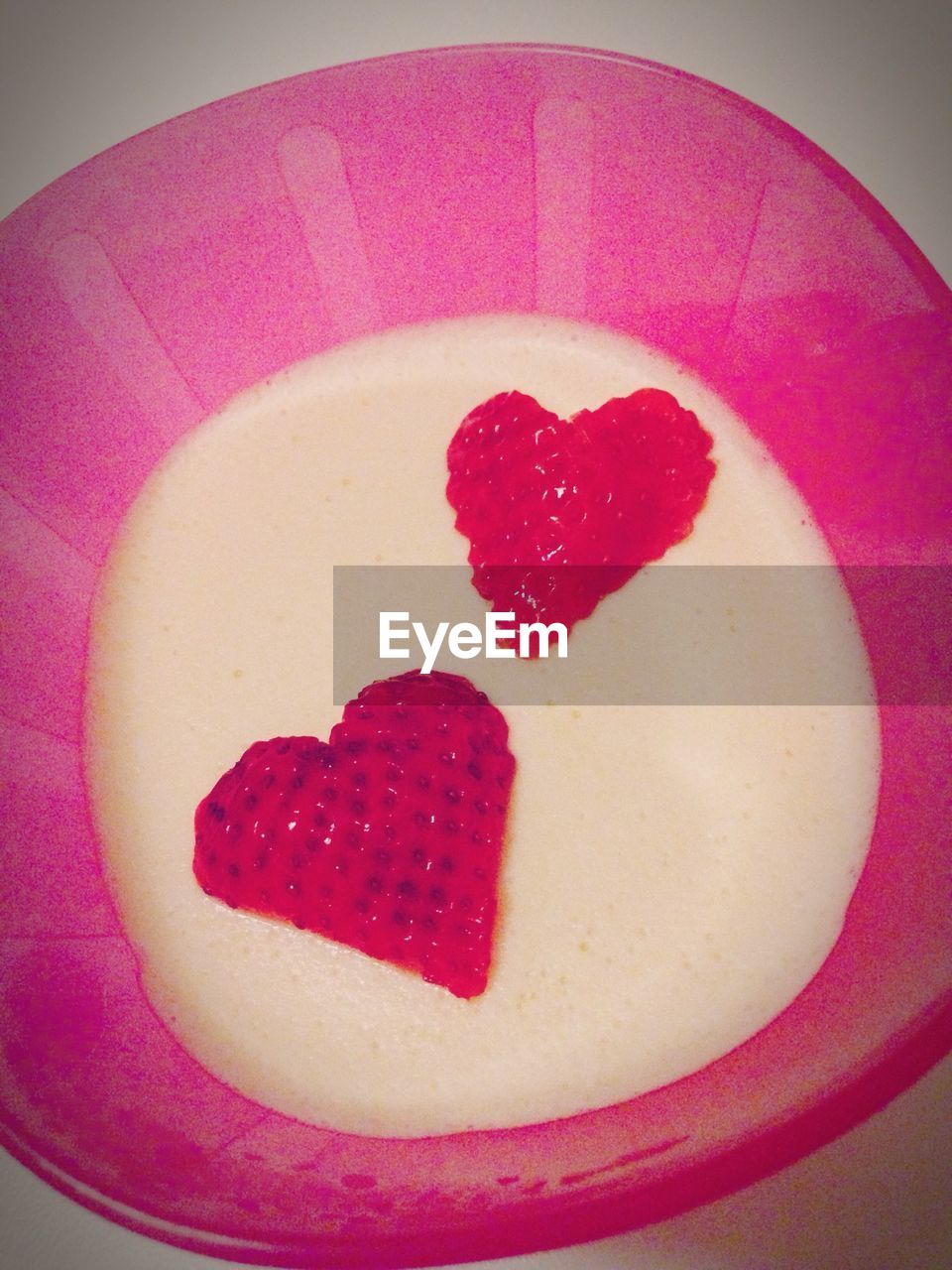Pudding garnished with heart shape strawberries in bowl