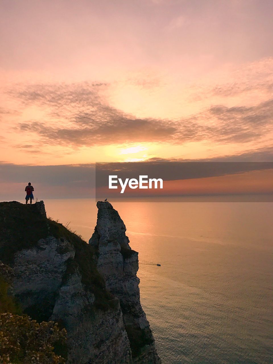 SILHOUETTE MAN STANDING ON ROCK AGAINST SKY DURING SUNSET