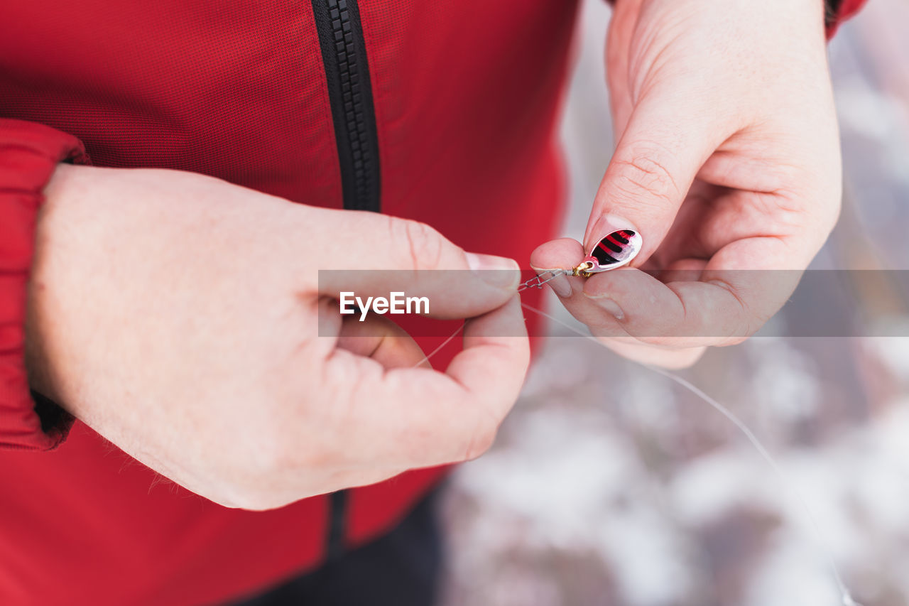 CLOSE-UP OF HAND HOLDING RED BLURRED OUTDOORS