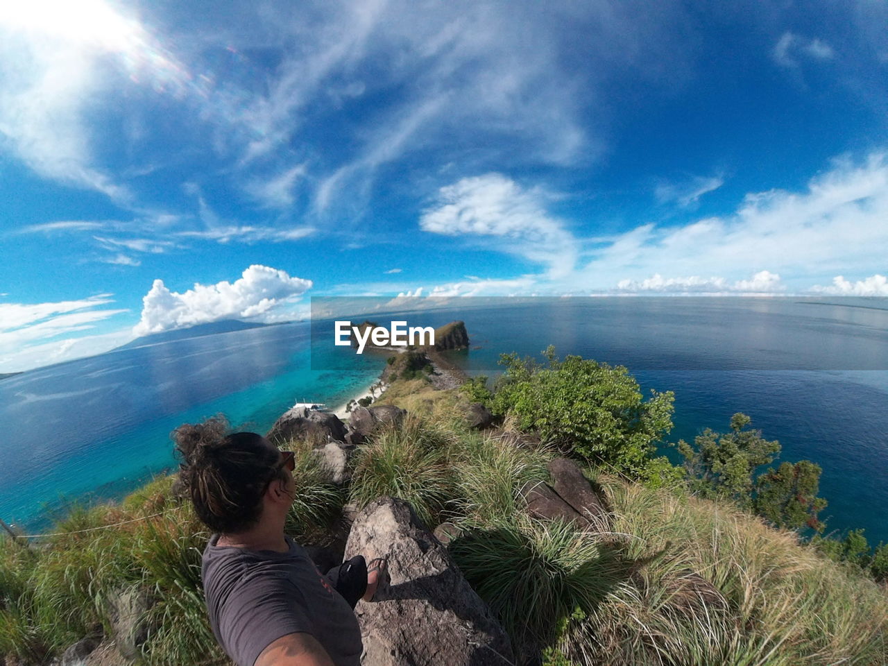 High angle view of man standing on cliff by sea against sky