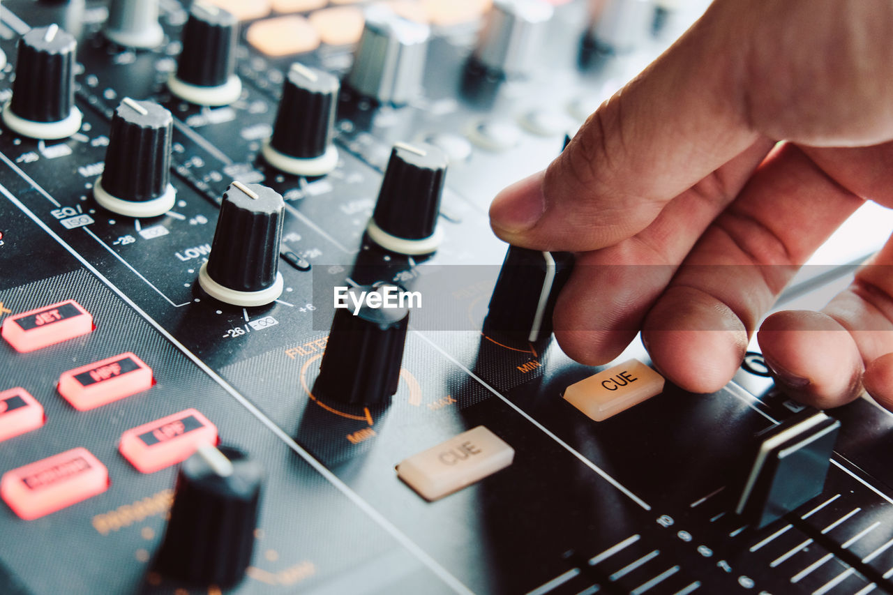 Cropped hand of musician adjusting sound mixer