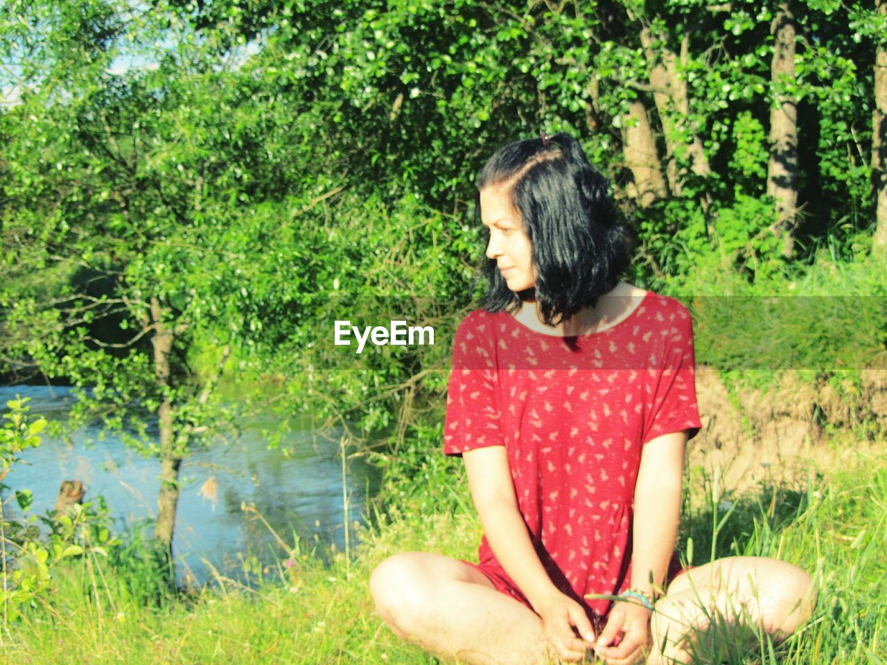 Young woman sitting on field during sunny day