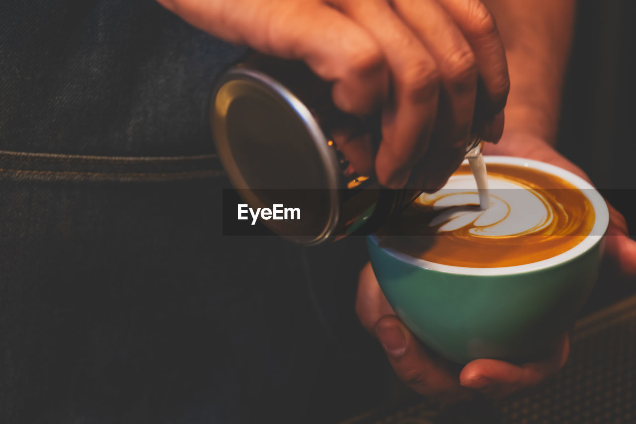 MIDSECTION OF MAN POURING COFFEE CUP