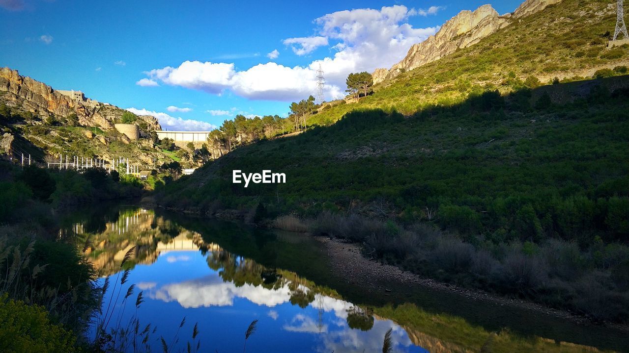 Scenic view of lake by mountains against sky