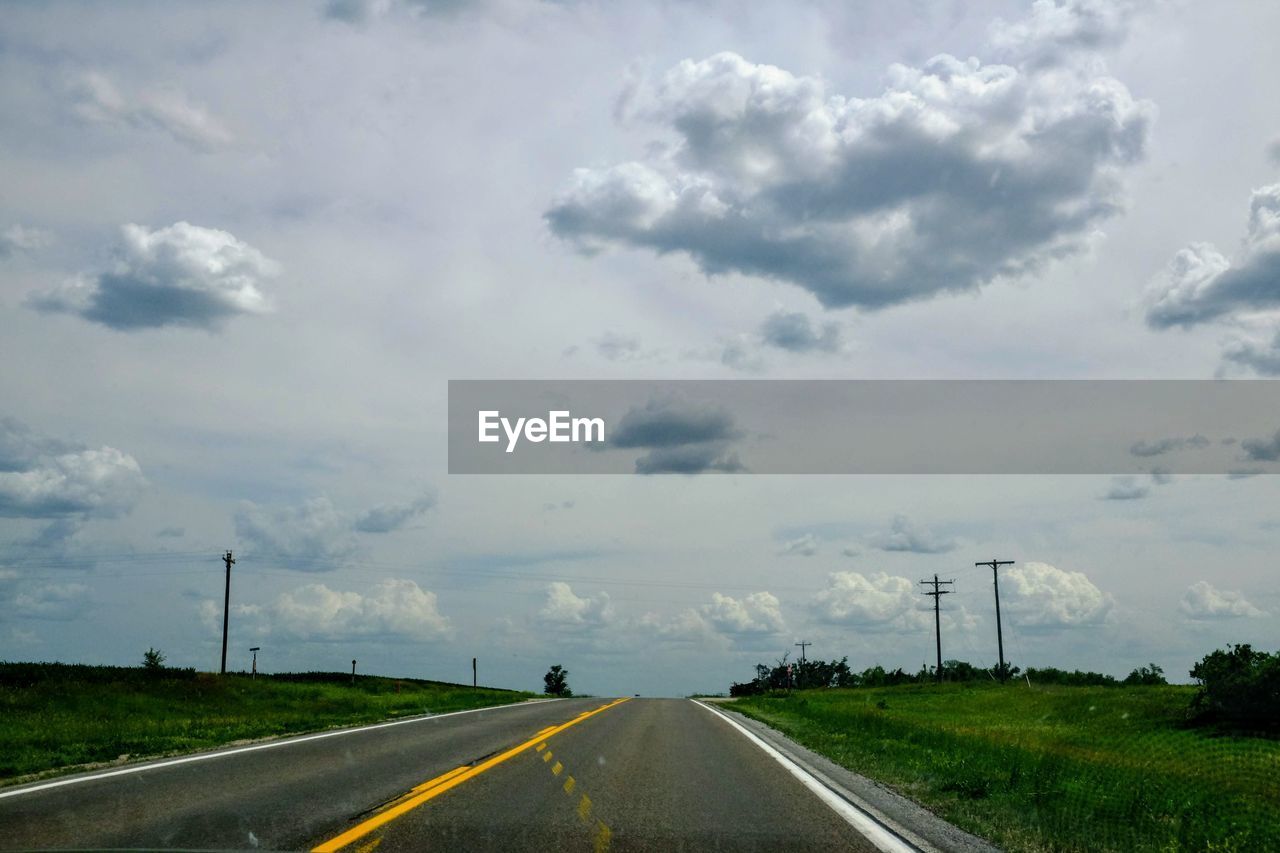 Country road against cloudy sky seen through windshield