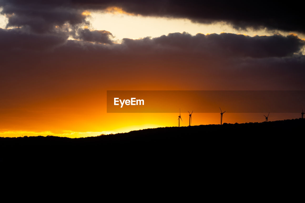 SILHOUETTE LANDSCAPE AGAINST DRAMATIC SKY DURING SUNSET