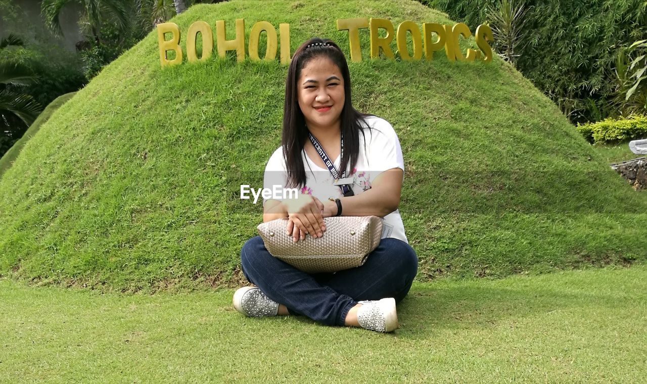 YOUNG WOMAN SITTING ON GRASS