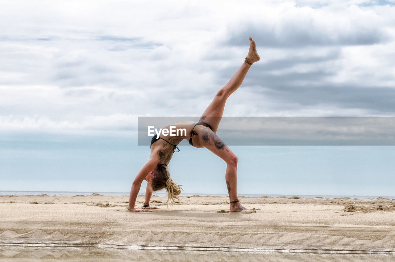 MAN WITH ARMS RAISED ON BEACH