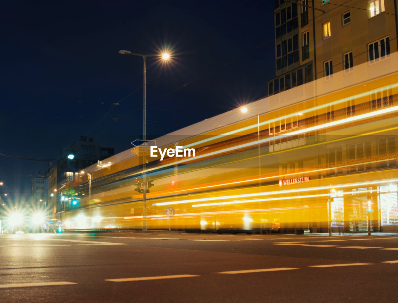 LIGHT TRAILS ON ROAD AGAINST SKY AT NIGHT