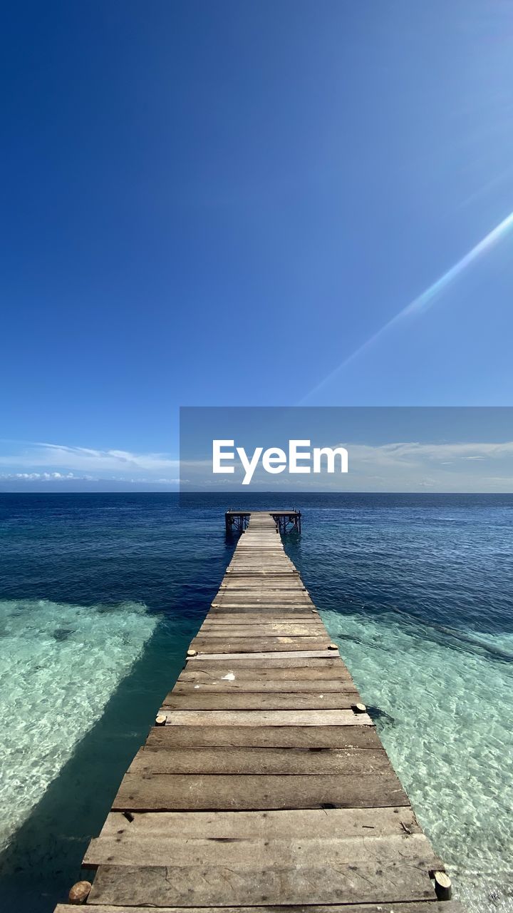 water, sky, sea, horizon, ocean, horizon over water, scenics - nature, beauty in nature, blue, the way forward, nature, shore, land, tranquility, beach, tranquil scene, pier, coast, wood, jetty, idyllic, sunlight, diminishing perspective, clear sky, wave, no people, day, cloud, outdoors, boardwalk, seascape, vanishing point, summer, footpath, body of water, travel destinations, holiday, sunny, non-urban scene, urban skyline, environment, travel, trip, reflection, vacation, bay, landscape