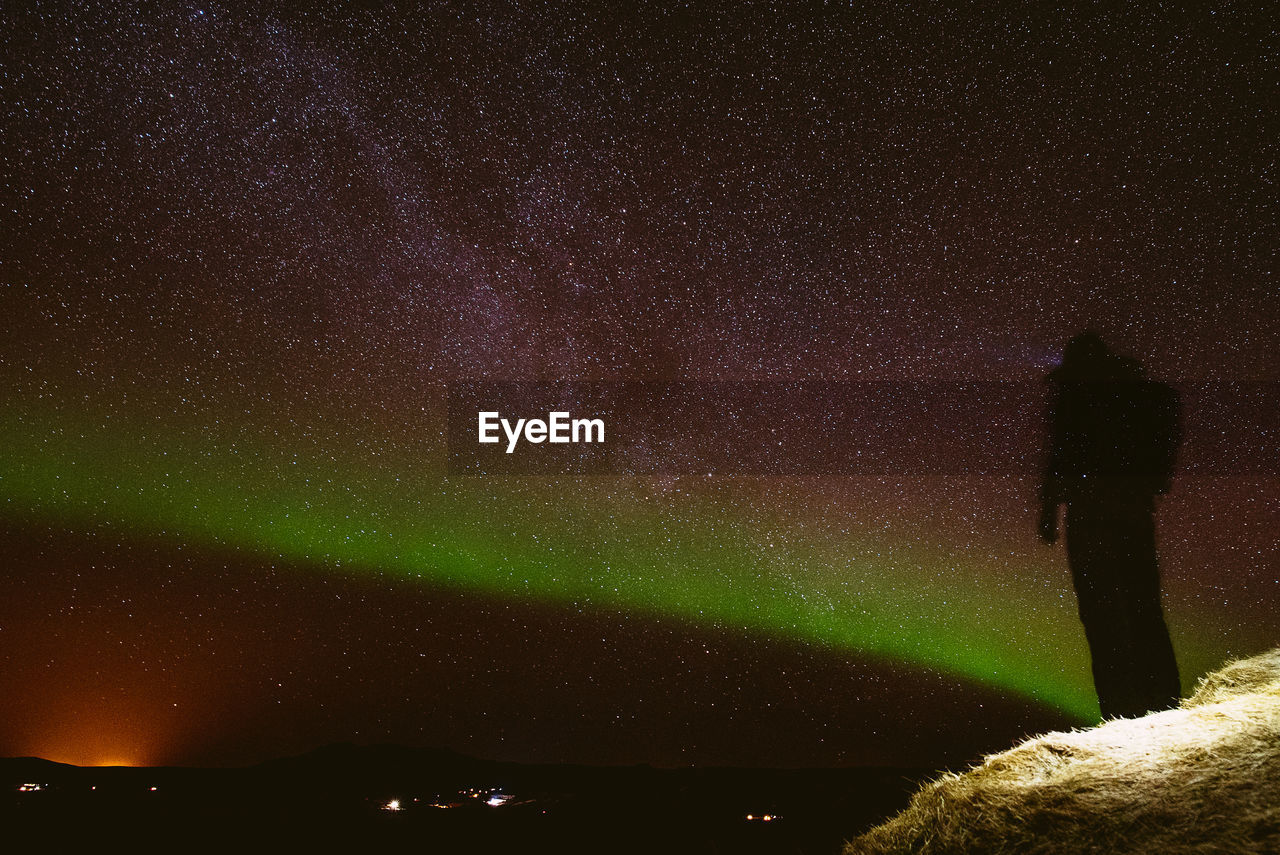 Low angle view of silhouette person standing on field against star field