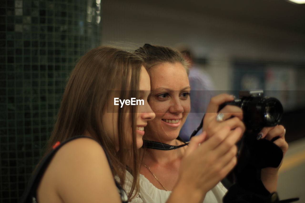 PORTRAIT OF A SMILING YOUNG WOMAN USING MOBILE PHONE