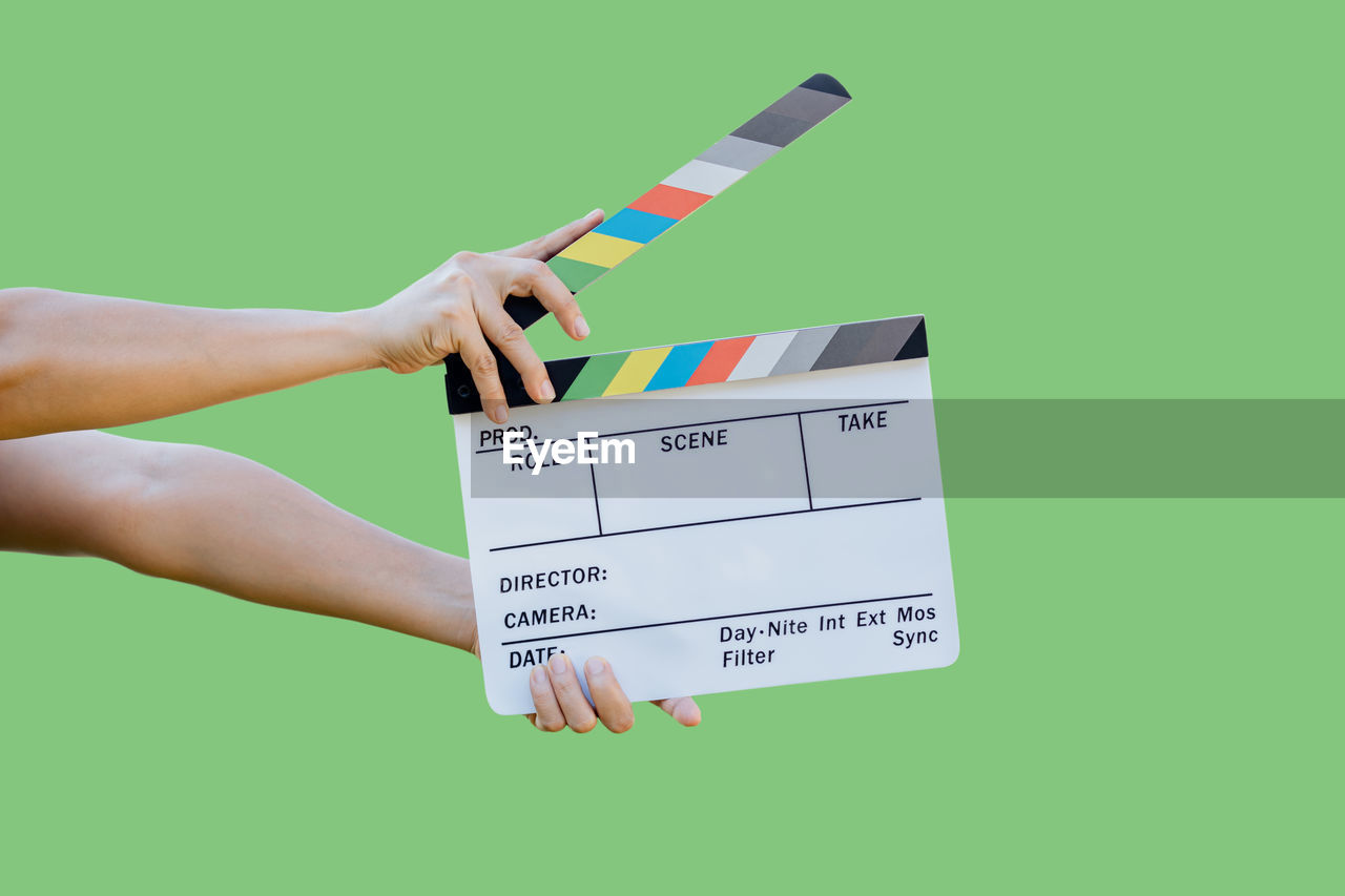 Hand holding film slate colors board for movie cinema and television industry on green background