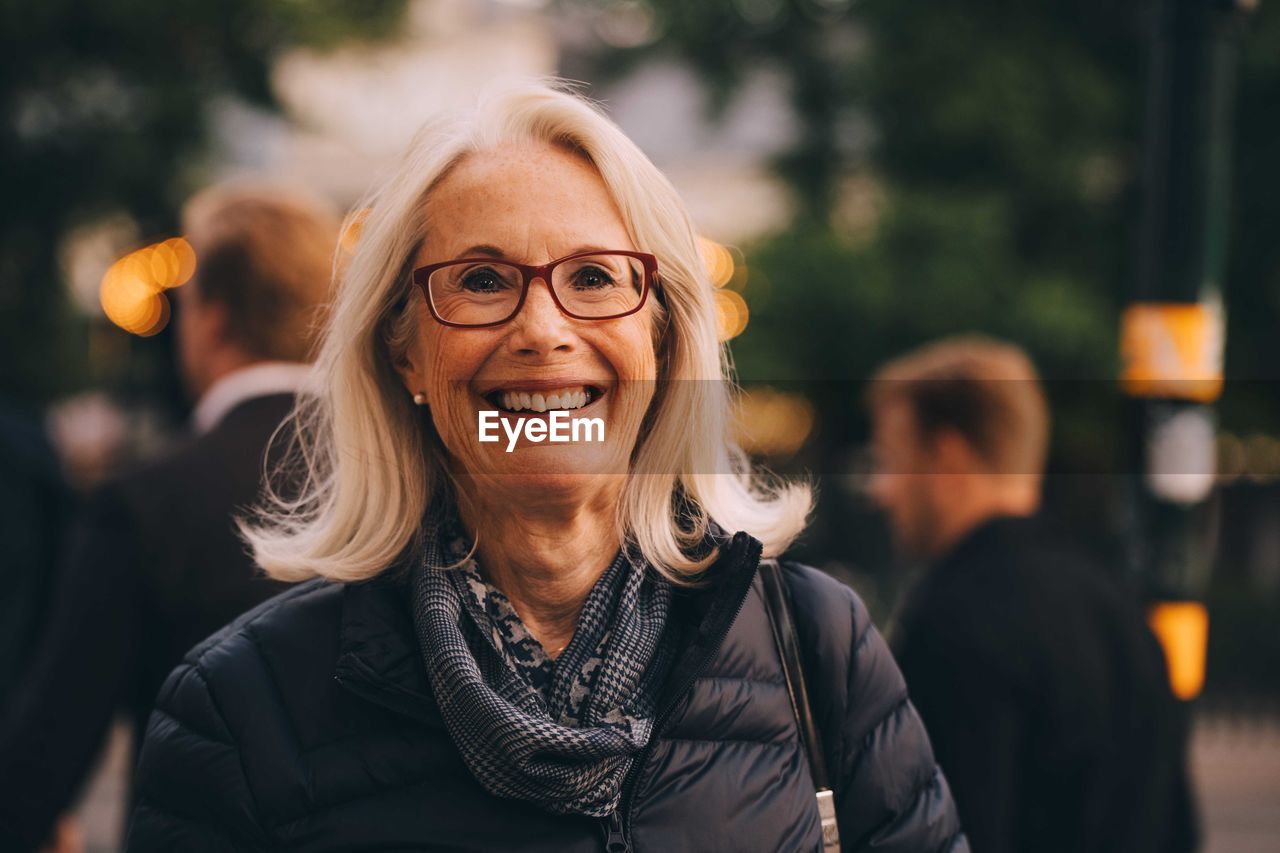 Portrait of smiling senior woman standing in city