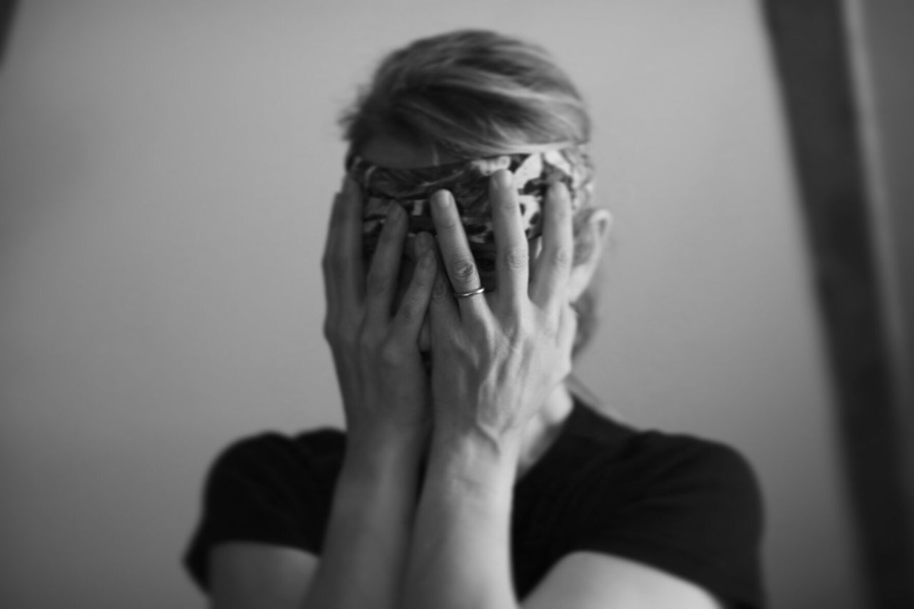 Close-up of woman covering face with hands at home