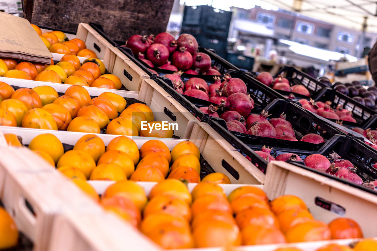 High angle view of persimmons and pomegranates for sale at market stall