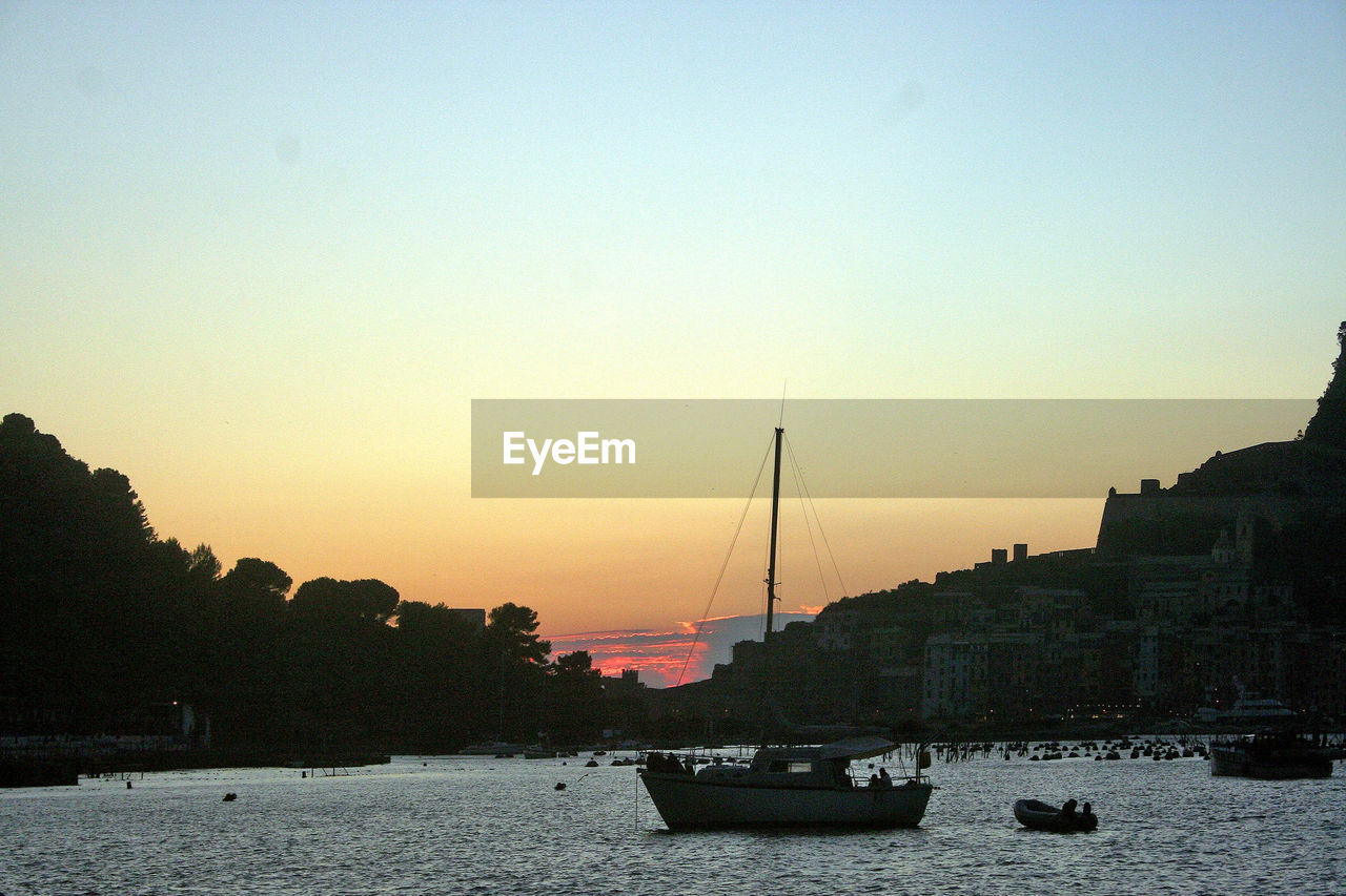 Sailboats moored on river against sky during sunset