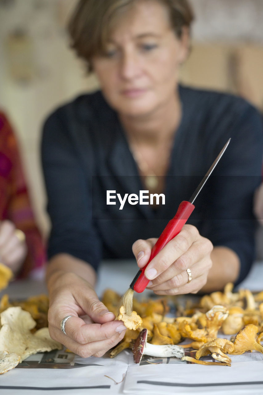 Mature woman cleaning chanterelle mushroom at home