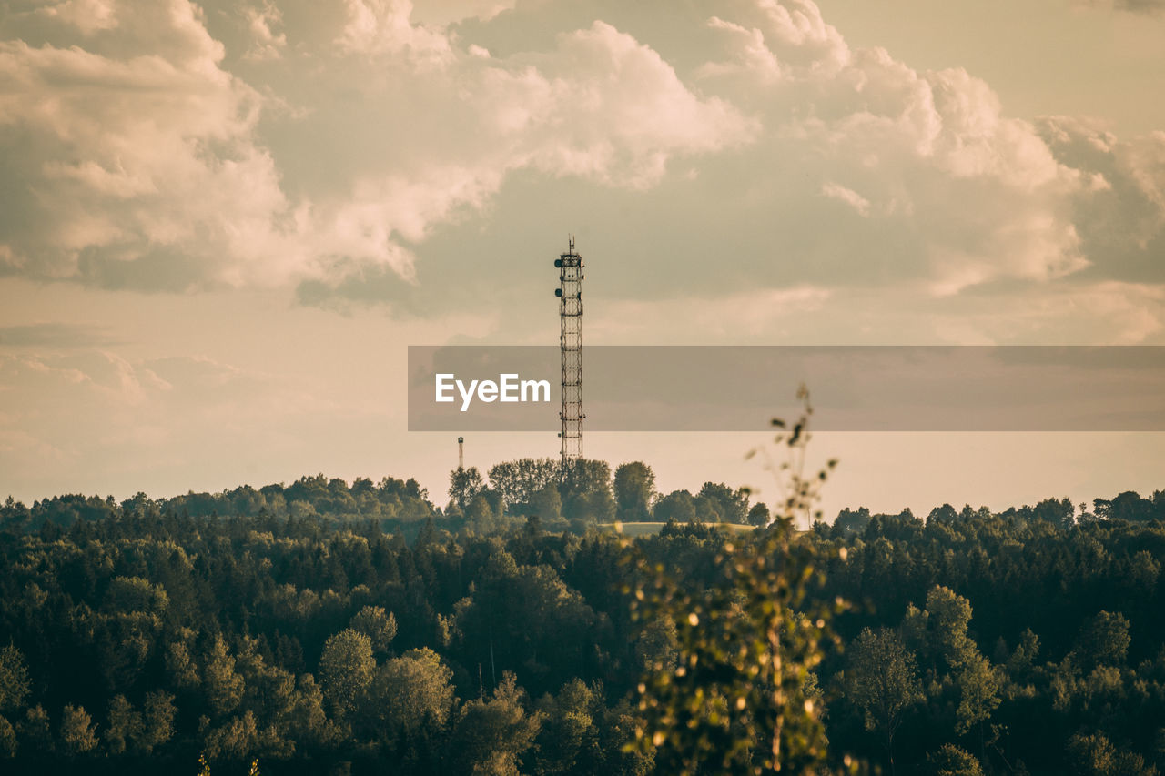 Panoramic view of communications tower and trees against sky