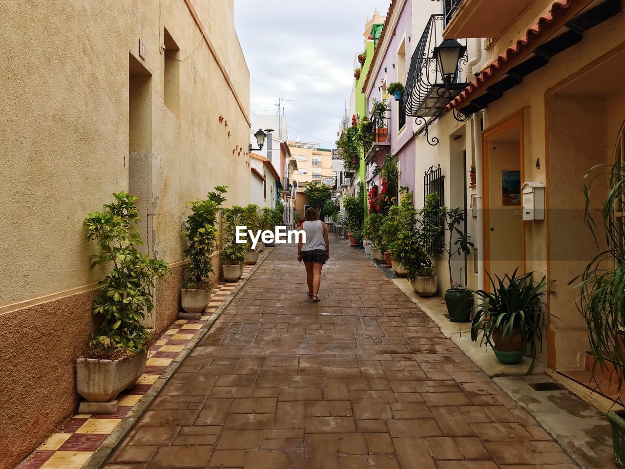 Rear view of woman walking on street amidst buildings in city